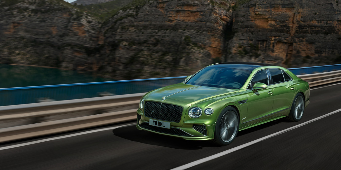 Bach Premium Cars GmbH Bentley New Flying Spur Speed v8 hybrid sedan driving dynamically on a mountain road in Tourmaline Green paint