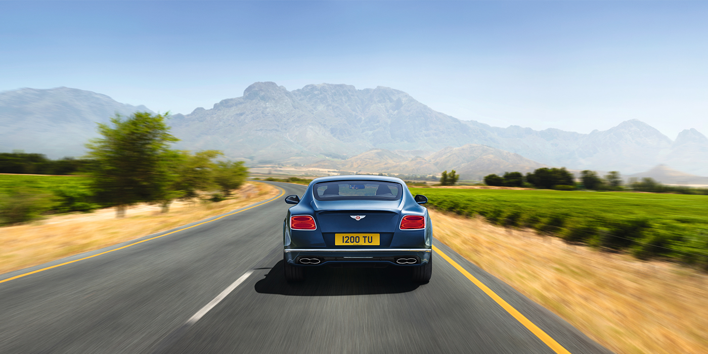 Bach Premium Cars GmbH Bentley Pre Owned Bentley Continental GT in Marlin blue paint seen from rear on country road