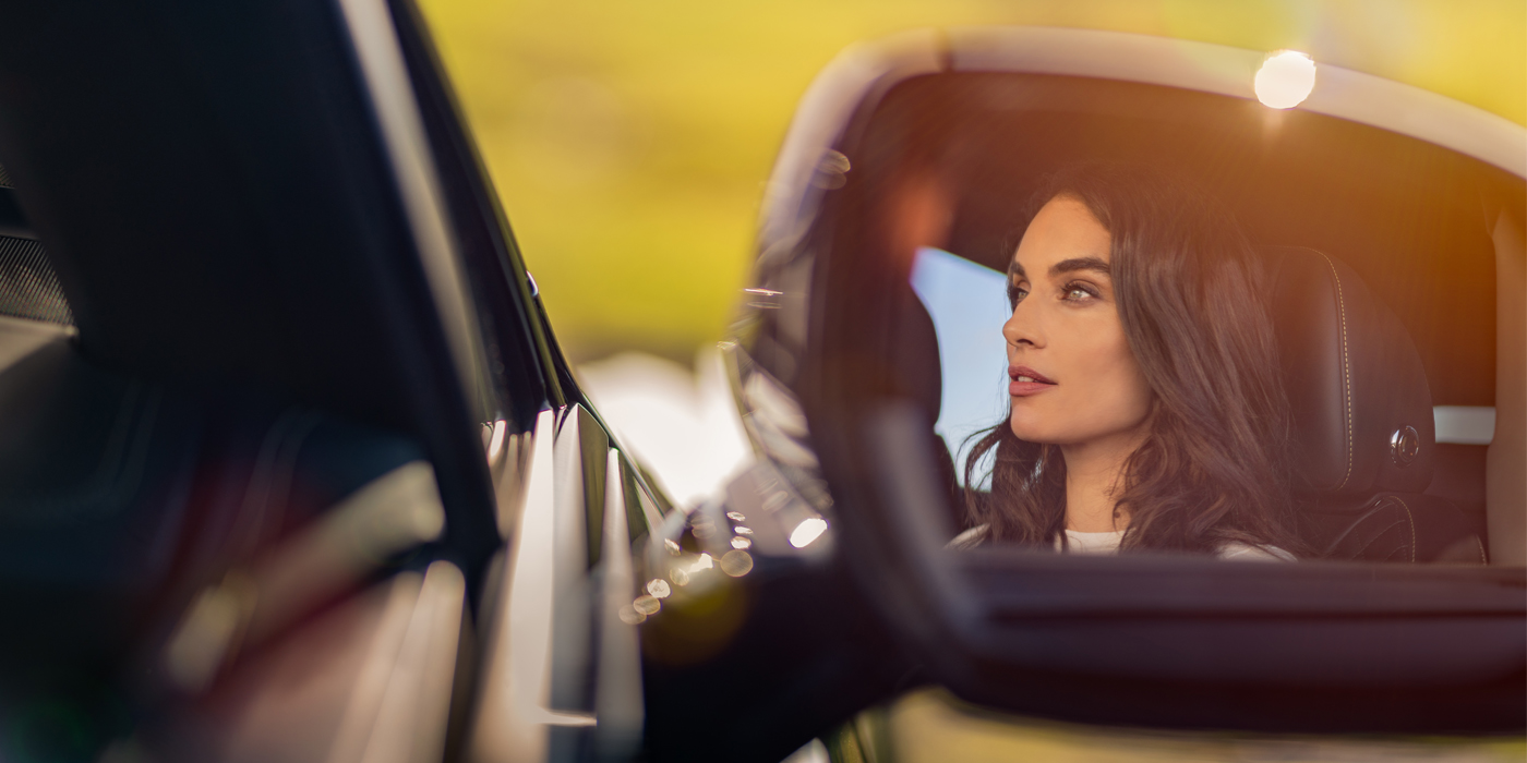 Bach Premium Cars GmbH profile of dark haired woman's face in mirror of Bentley car in sunlight