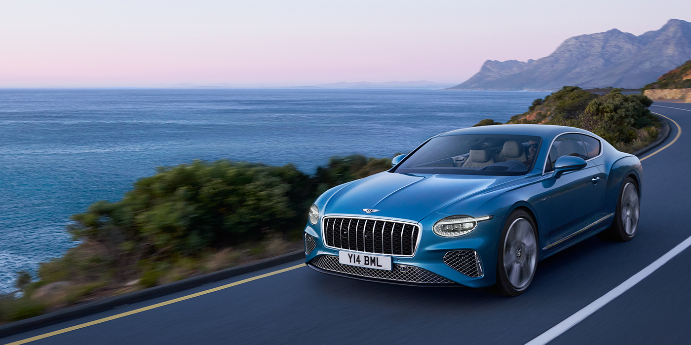 Bach Premium Cars GmbH New Bentley Continental GT Azure coupe in Light Windsor blue paint with 22 inch Azure wheels and chrome grill, driving dynamically by the sea