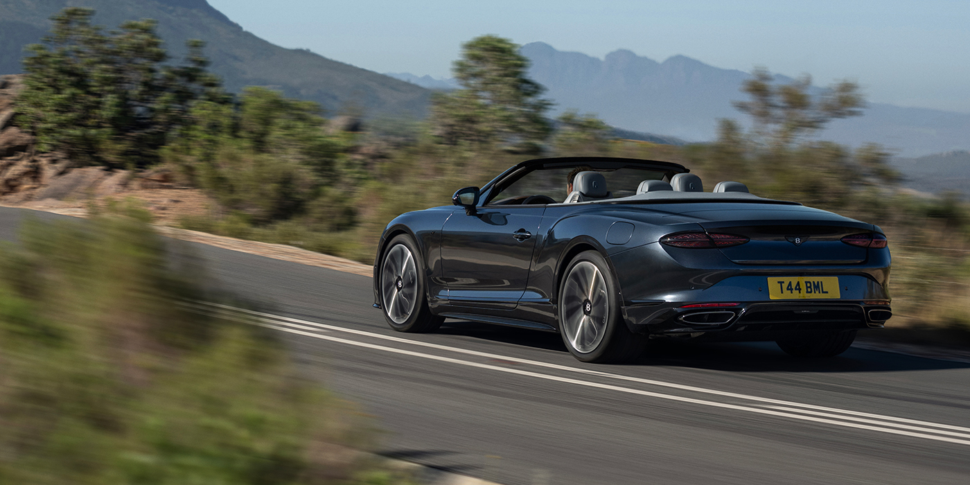 Bach Premium Cars GmbH Bentley Continental GTC S convertible in Thunder blue paint rear 3/4 driving on mountain road