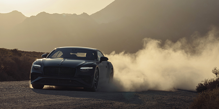 Bach Premium Cars GmbH Bentley Continental GT coupe in Thunder paint front 3/4 driving with dust trail at sunset