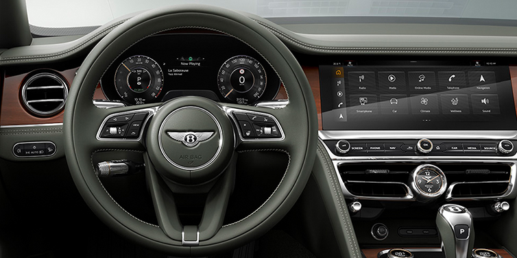 Bach Premium Cars GmbH New Bentley Flying Spur front cabin interior in Cumbrian green hide with Crown Cut walnut veneer showing steering wheel and driver controls
